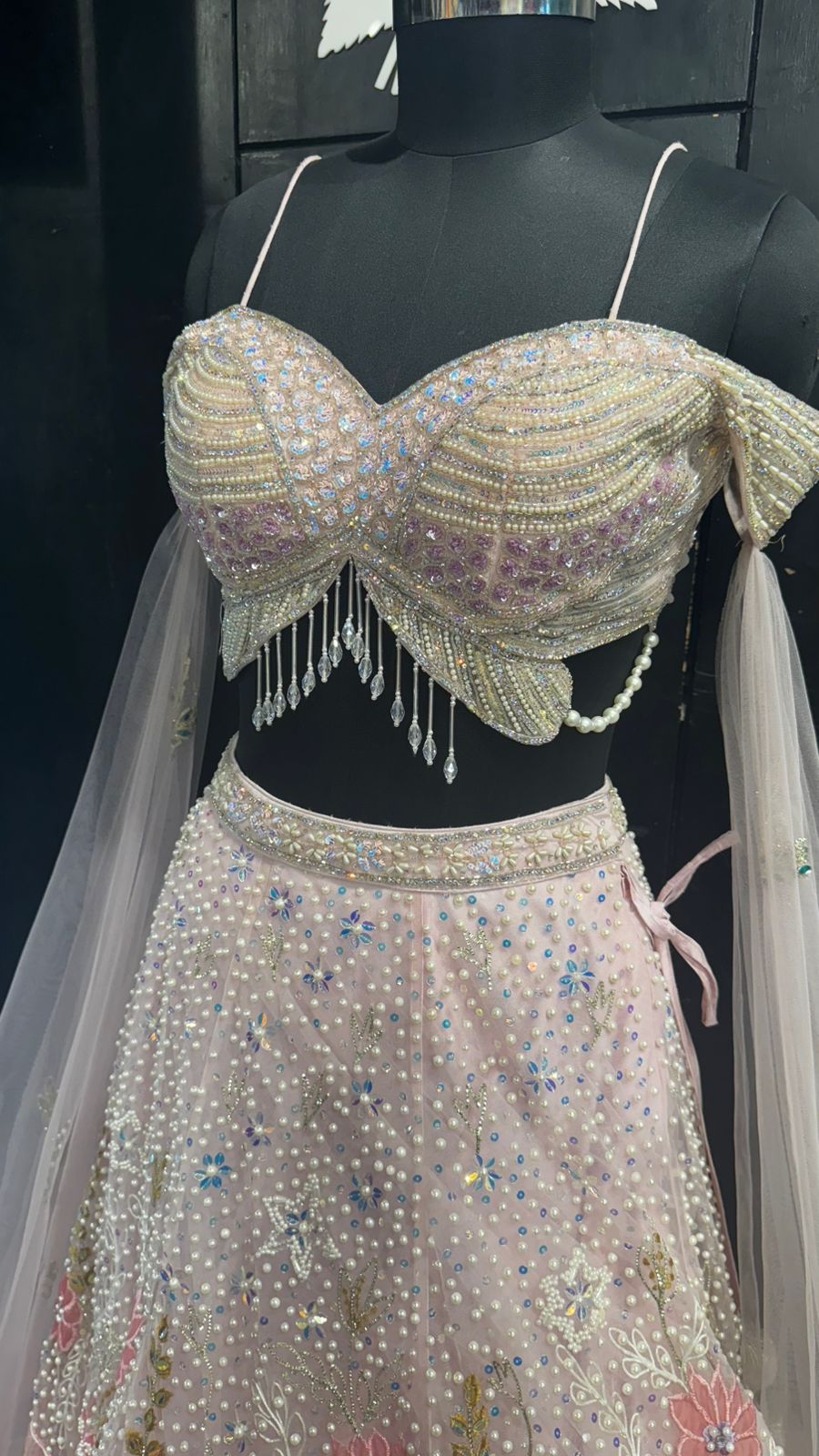 Imported Net Powder Pink Lehenga with beautiful handwork in pearl and beads teamed with full handwork blouse with tassels and dropping dupatta coming from behind the top for amazingly angelic appeal