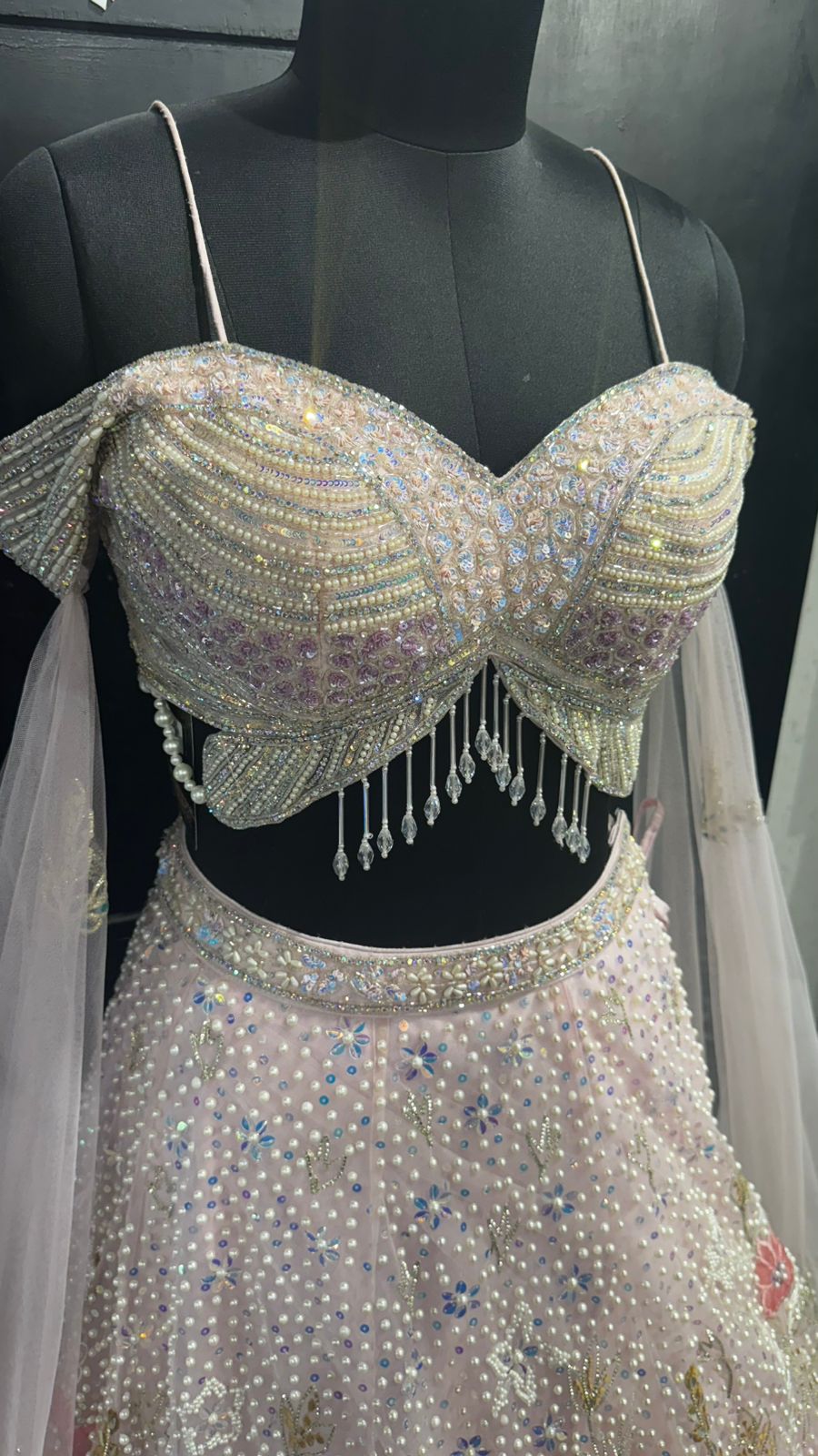 Imported Net Powder Pink Lehenga with beautiful handwork in pearl and beads teamed with full handwork blouse with tassels and dropping dupatta coming from behind the top for amazingly angelic appeal